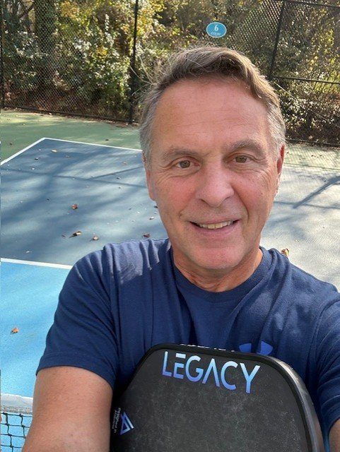 Coach Steve Sarago smiling courtside with his paddle